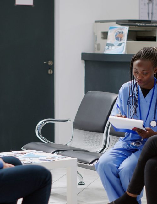 medical-assistant-doing-consultation-with-patient-hospital-reception-lobby-sitting-waiting-room-talking-about-healthcare-treatment-nurse-giving-advice-young-adult